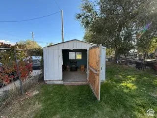 Storage shed with an open wooden door and a single window, set on a concrete foundation