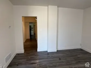 Wood-finish flooring with white baseboards and an open doorway