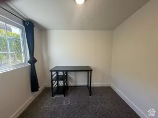 Wall-to-wall carpeting, white walls, and a window with natural light