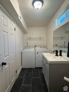 Recessed laundry area with dark tile flooring, a single vanity with a white countertop and basin, and a transom window
