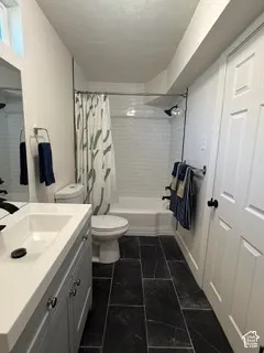 Bathroom featuring a single vanity with storage, a white rectangular sink, dark floor tiling, and a shower-over-tub combination with white subway tile surround
