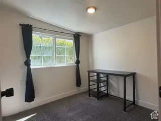 Window with grid pattern, neutral wall finish, flush mount ceiling light, and textured carpet flooring
