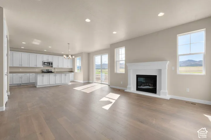 Spacious open-concept layout with wood-finish flooring, a white mantel fireplace, and recessed lighting