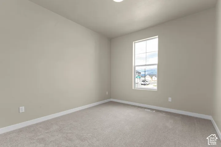Neutral-toned walls, plush carpeting, and a large window with white trim