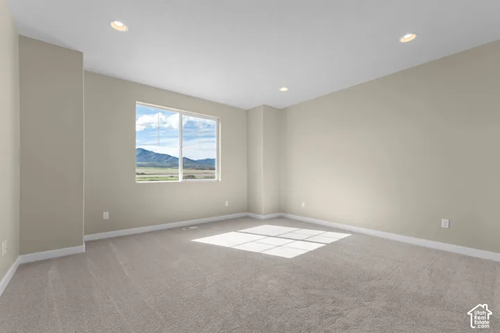 Recessed lighting illuminates neutral-toned walls and plush carpeting, complemented by a large window with a distant mountain backdrop