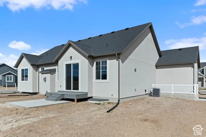 Stucco exterior with a dark shingle roof, featuring a rear sliding glass door and a small wood-finish deck