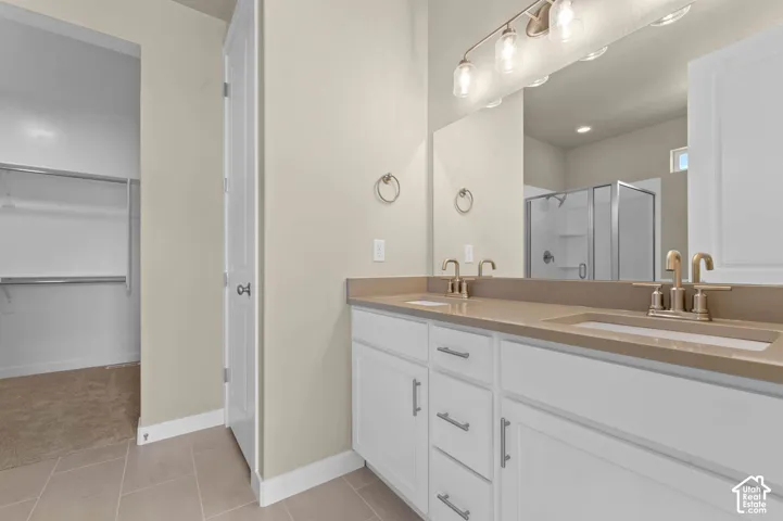 Bathroom featuring a dual vanity with light-colored countertops, white cabinetry, and brushed gold fixtures