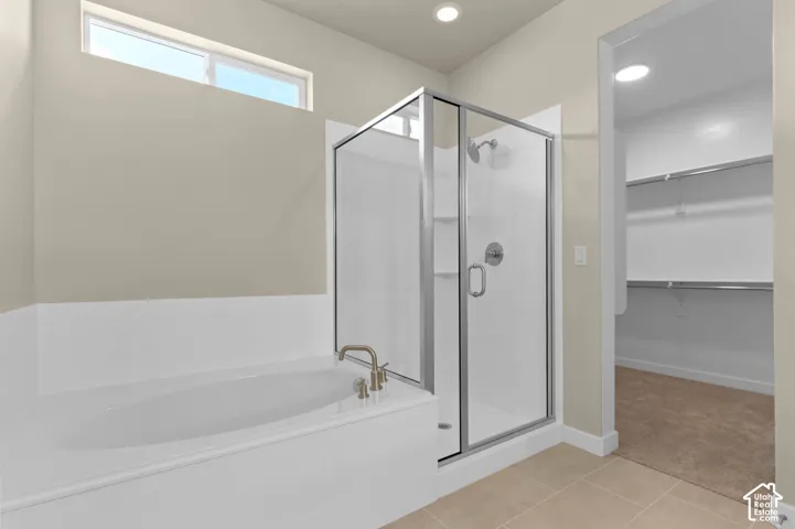 Soaking tub with brushed nickel fixtures, glass-enclosed shower with chrome hardware, and tile flooring
