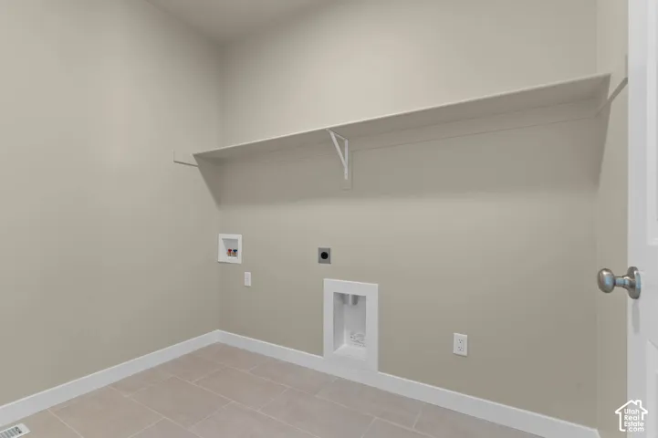 Laundry area with neutral wall color, tile flooring, and a built-in shelf