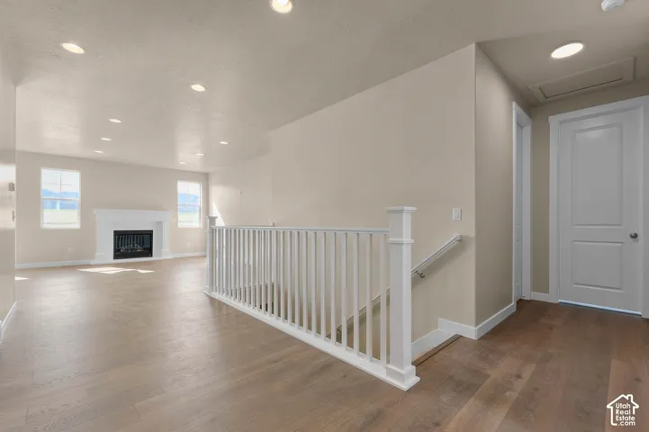 Recessed ceiling lighting, wood-finish flooring, white fireplace with mantle, white interior doors, and white baluster railing