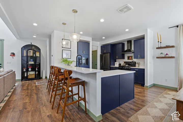 Kitchen featuring blue cabinetry, white quartz countertops, stainless steel appliances, and a stylish range hood