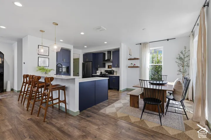 Open-concept kitchen and dining area featuring wood-finish flooring, recessed lighting, and a kitchen island with pendant lighting