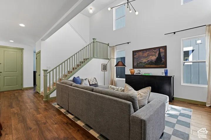 Two-story living area with wood-finish flooring, a contemporary chandelier, and multiple windows