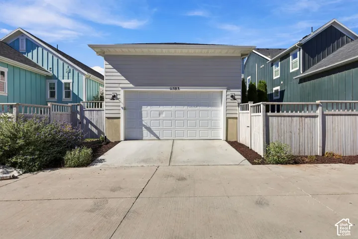 Attached two-car garage with overhead door, concrete driveway, and exterior lighting fixtures