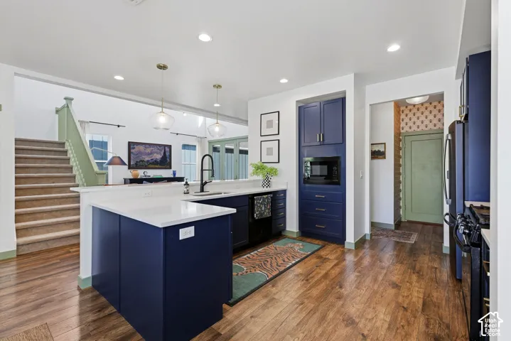 Modern kitchen featuring navy cabinetry, quartz, white countertops, built-in microwave, wood-finish flooring, and recessed lighting