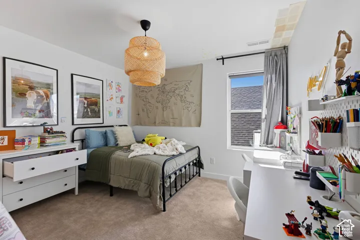 Carpeted room featuring a single window, a built-in desk, shelving, and a decorative ceiling light fixture