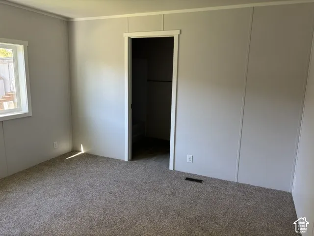 Carpeted flooring, light-toned wall panels, white trim, and a functional window