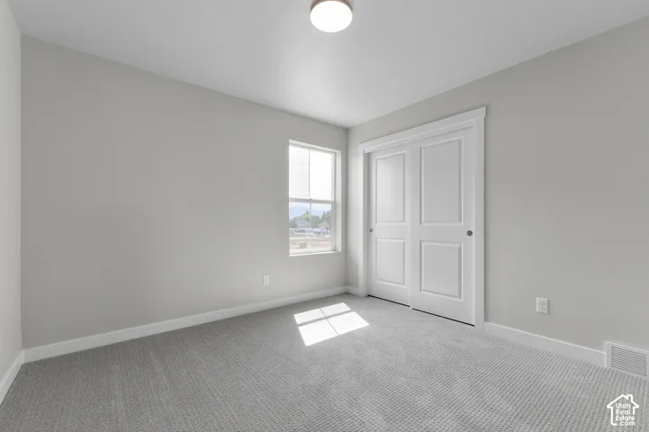 Light gray wall finish, gray carpet, white trim, white bi-fold closet doors, and a ceiling-mounted light fixture