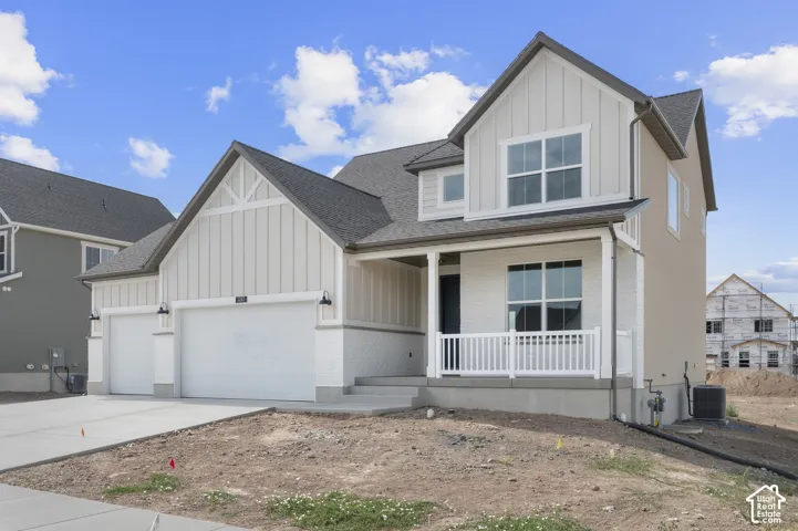 Two-story exterior with board and batten siding, white brick accents, a covered front porch with white railing, and an attached two-car garage