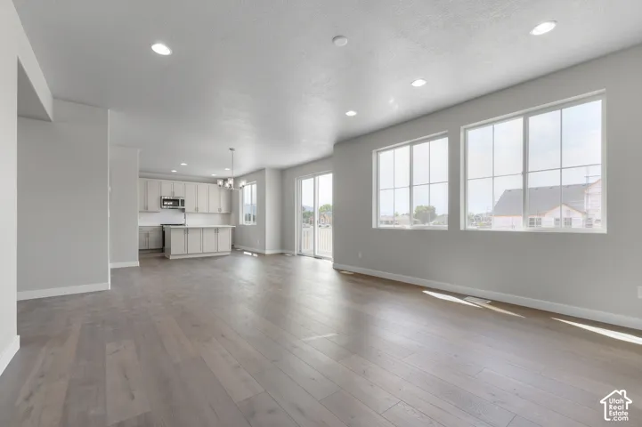 Open-concept living space featuring wood-finish flooring, recessed lighting, a modern kitchen with light-toned cabinetry, and large multiple-pane windows