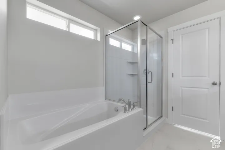 Soaking tub with brushed nickel fixtures, glass-enclosed shower, transom window, recessed lighting, and panel door