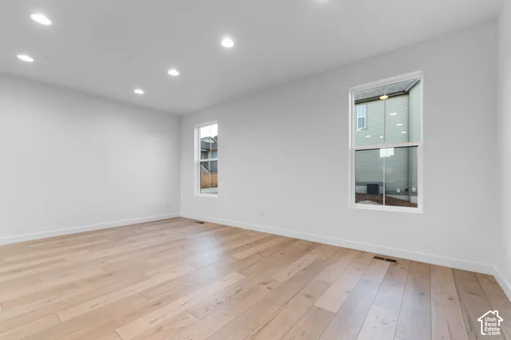 Recessed lighting, light wood-finish flooring, and white walls