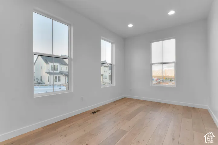 Light-toned wood-finish flooring, recessed lighting, and multiple windows