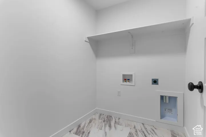 Laundry area featuring a built-in shelf, plumbing hookups, electrical outlet, and wood-finish flooring