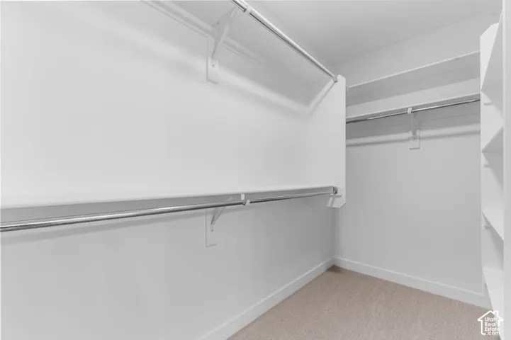Custom closet organization system featuring white shelving and chrome hanging rods