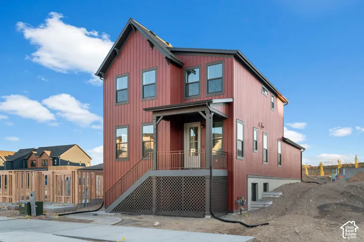Red vertical siding, dark trim windows, covered porch, exterior stairs with railing, and a gabled roofline