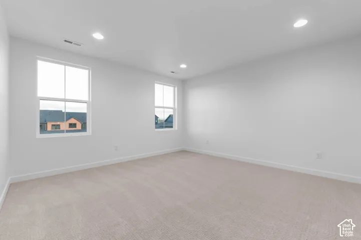 Recessed lighting, two windows, wall-to-wall carpeting, and neutral wall tones