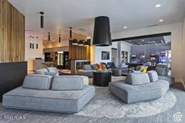 Open-concept living area with light-toned flooring, modern recessed lighting, and a suspended black light fixture