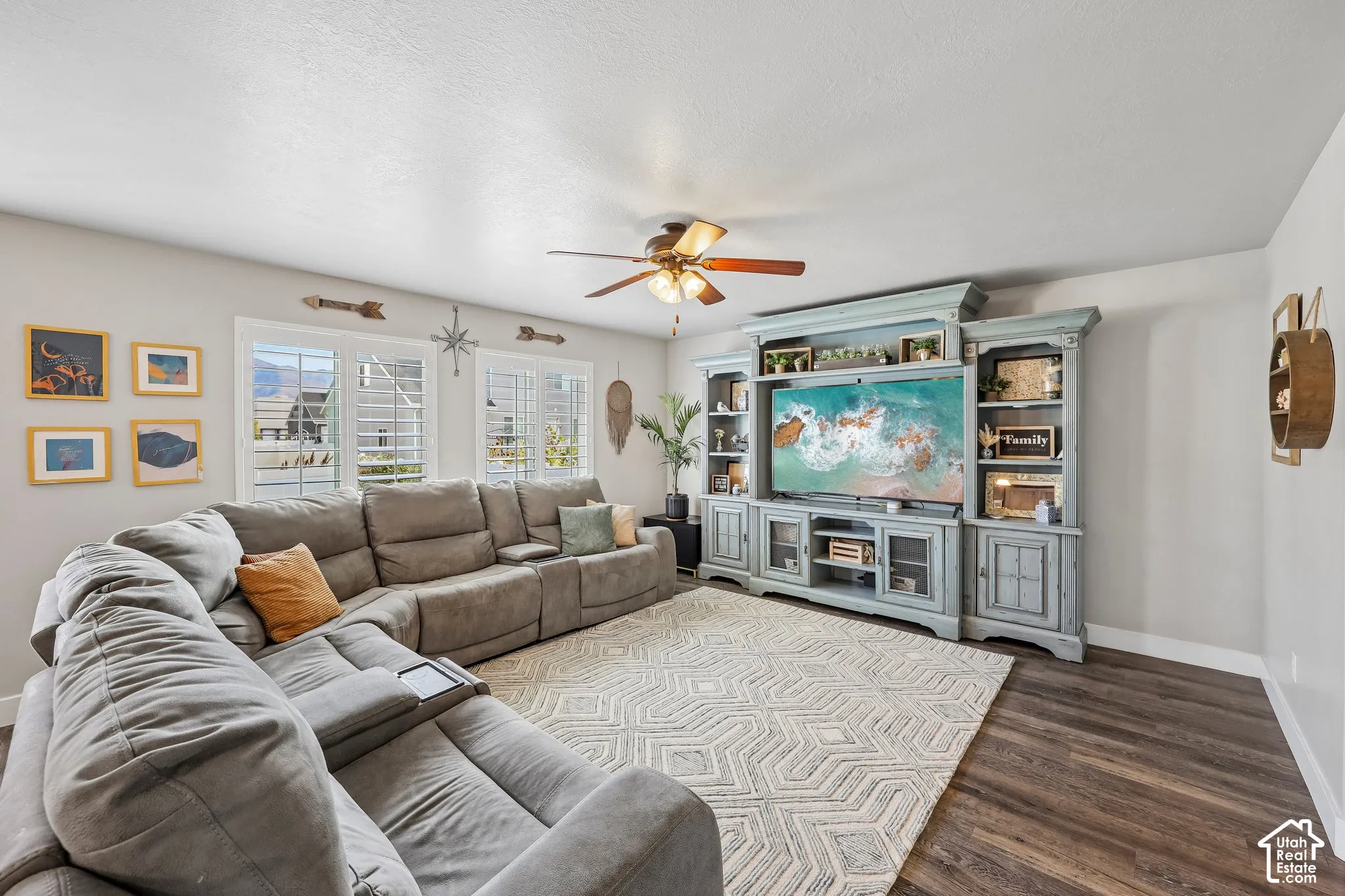 Spacious recreation room featuring a sectional-ready layout with wood-finish flooring, a geometric area rug, and an entertainment wall with built-in cabinetry and shelving