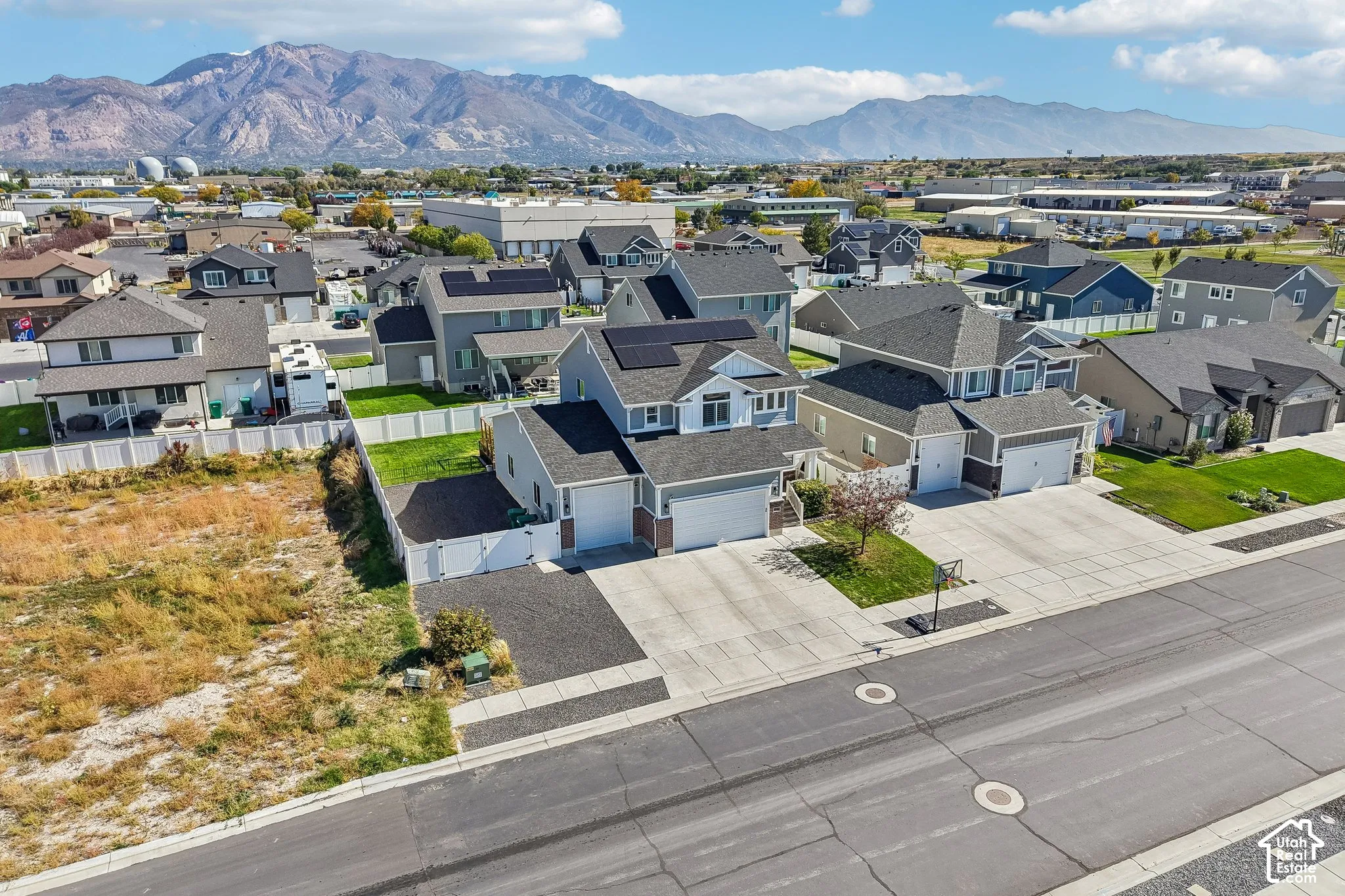 Mountain backdrop, residential neighborhood with single-family homes, established paved roadways, and a clear blue sky