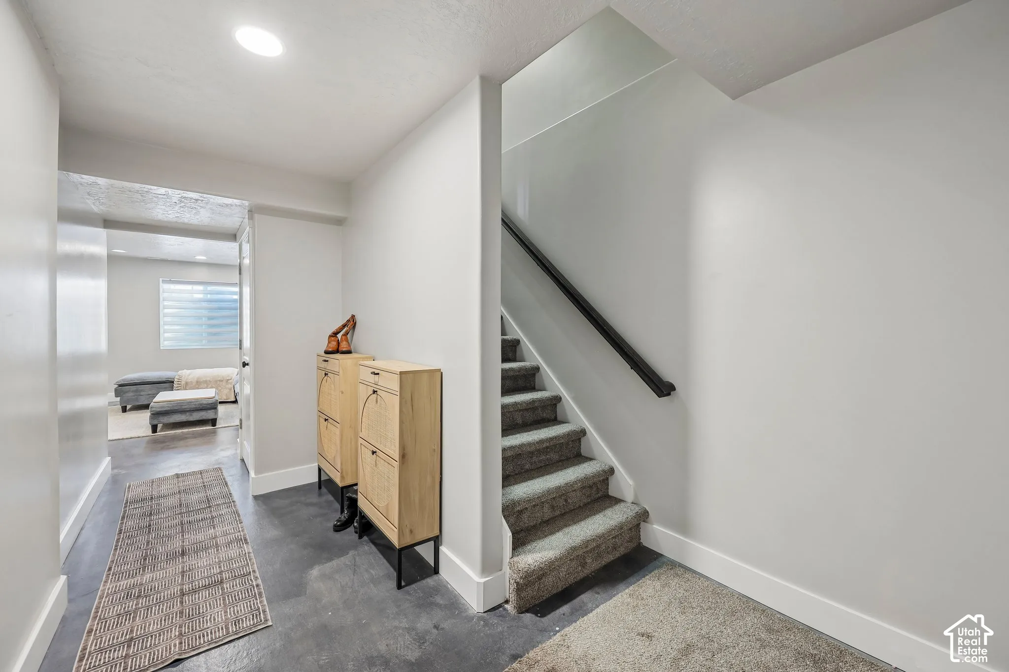 Recessed lighting illuminates the hallway with concrete-finish flooring