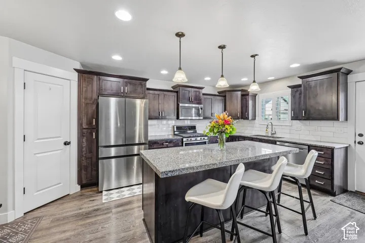 Modern kitchen featuring dark wood cabinetry, stainless steel appliances, and a large granite-topped island with seating for multiple guests