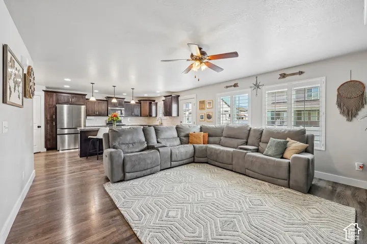 Open-concept living space featuring a sectional seating arrangement, wood-finish flooring throughout, and abundant natural light from multiple large windows