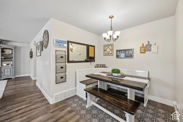 Bright dining area featuring a wood-finish table with matching bench seating, wood-look flooring throughout, and a pendant light fixture