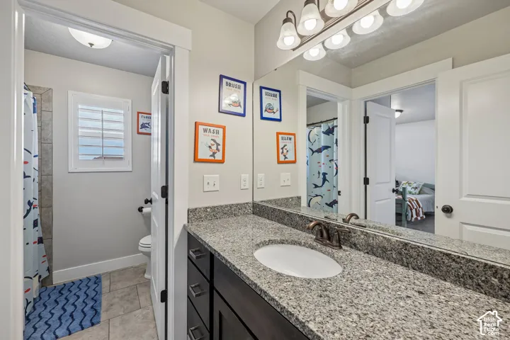 Vanity with a granite countertop, undermount sink, and dark wood-finish cabinetry