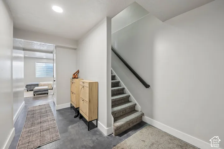 Recessed lighting illuminates the hallway with concrete-finish flooring