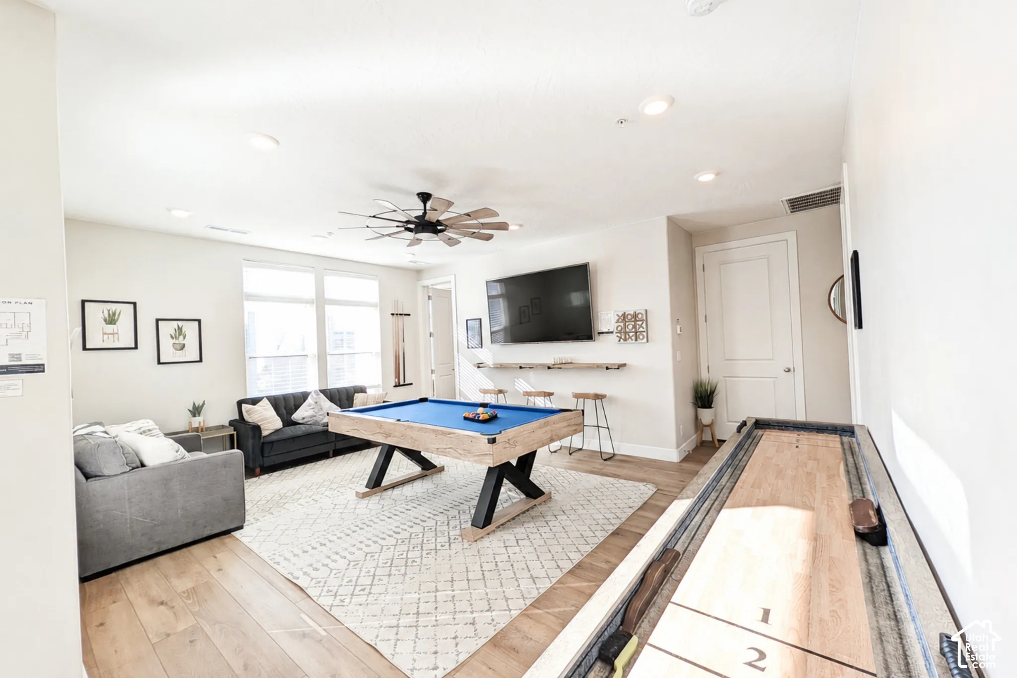 Recessed lighting illuminates wood-finish flooring and a ceiling fan