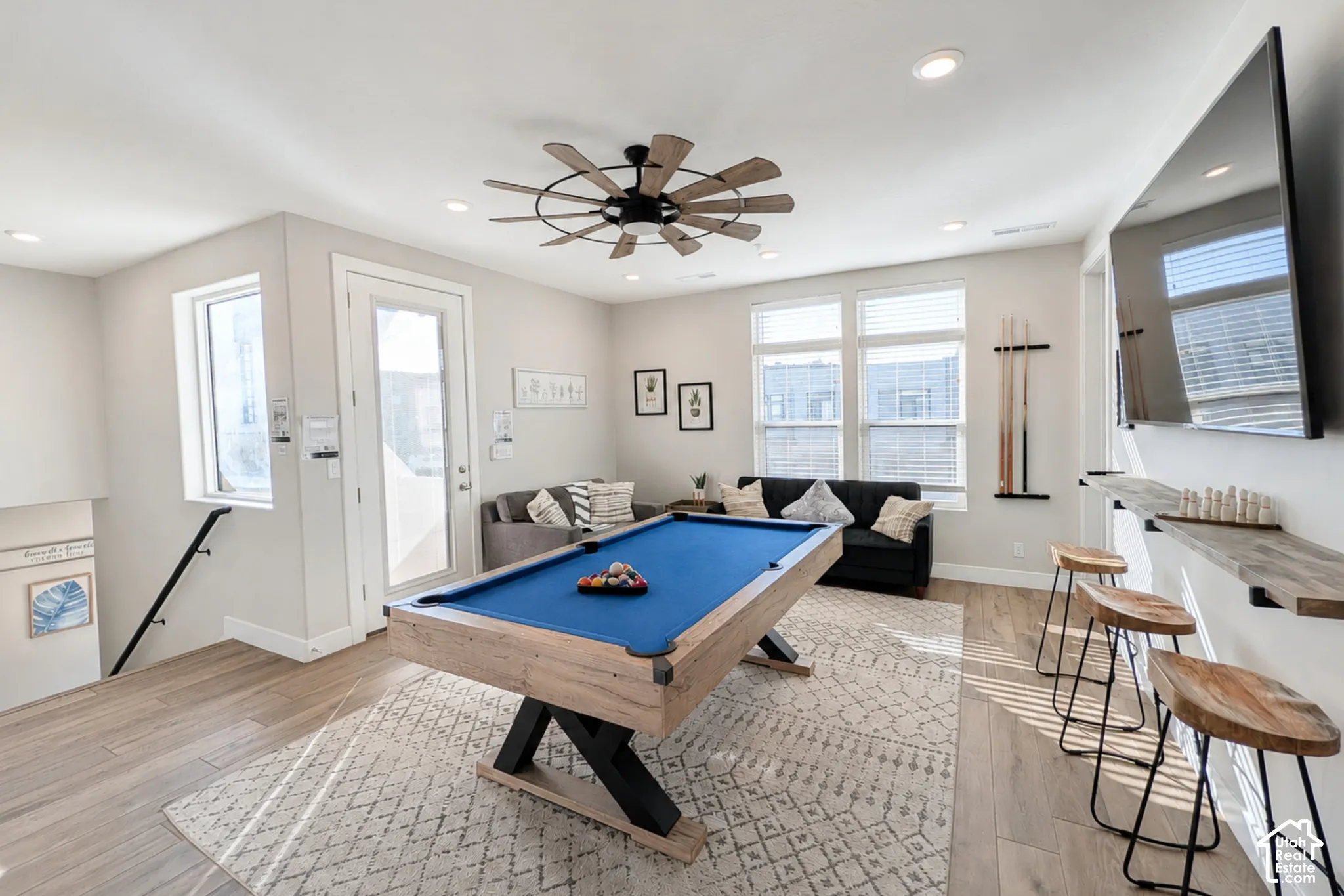 Recessed lighting, wood-finish flooring, a contemporary ceiling fan, and multiple windows with blinds