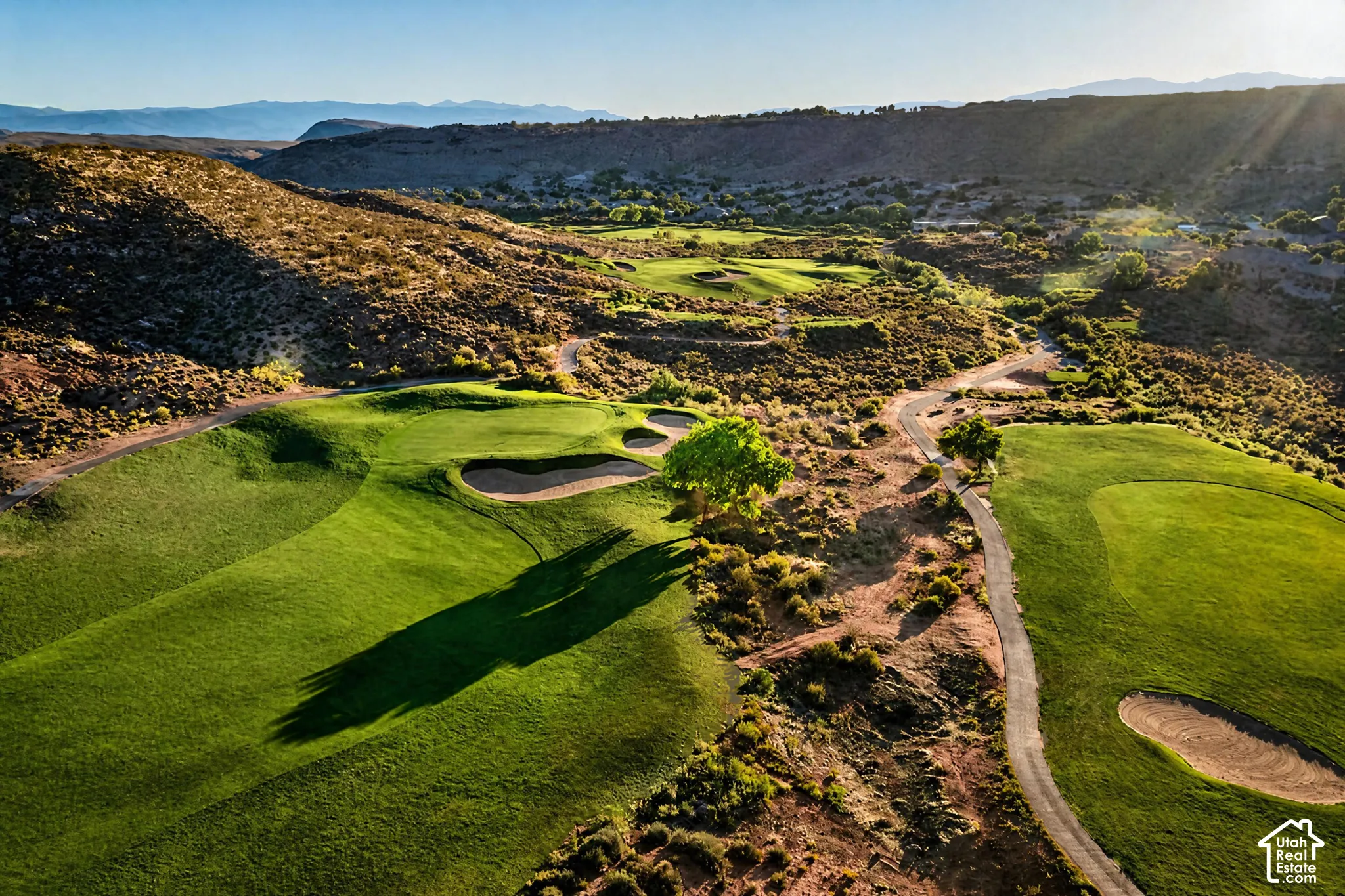 Expansive golf course featuring manicured green fairways, sand traps, and paved cart paths