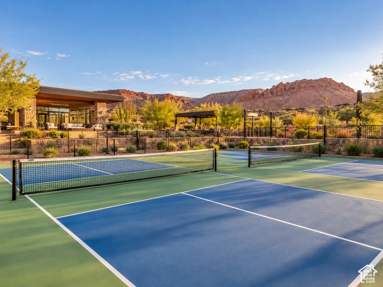 Multiple outdoor courts with blue and green surfaces, featuring white boundary lines and black nets