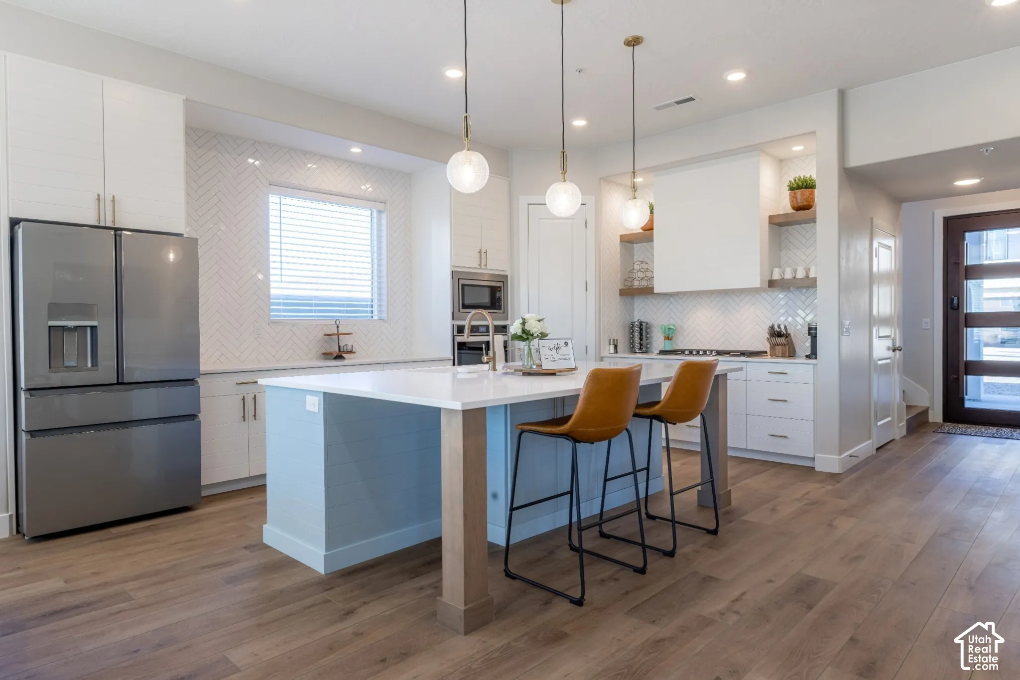 Kitchen featuring wood-finish flooring, a light blue island with a white countertop, and pendant lighting