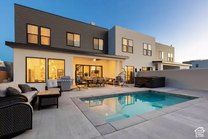 Modern exterior with contrasting siding, large windows, an integrated covered patio, a built-in swimming pool, and a hot tub