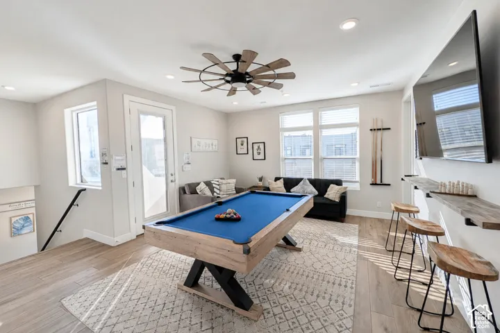 Recessed lighting, wood-finish flooring, a contemporary ceiling fan, and multiple windows with blinds