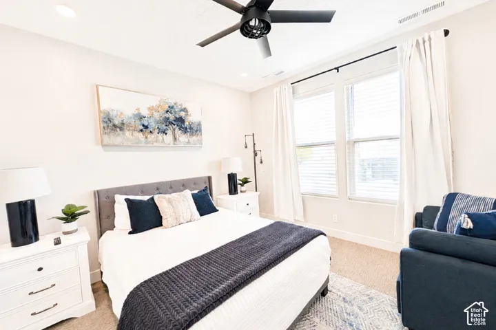 Recessed ceiling lighting, ceiling fan, carpeted flooring, large windows with blinds, and white curtains