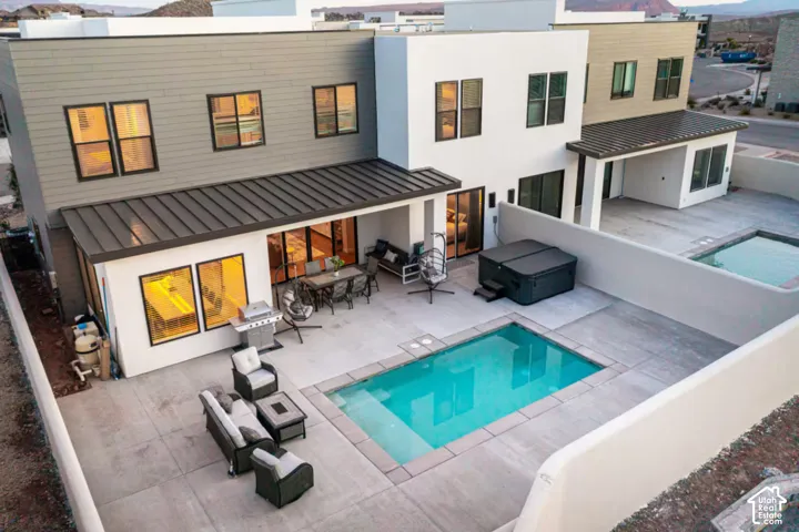 Rear exterior featuring a rectangular pool, covered patio, hot tub, and an additional pool