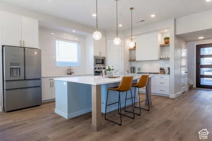 Kitchen featuring wood-finish flooring, a light blue island with a white countertop, and pendant lighting